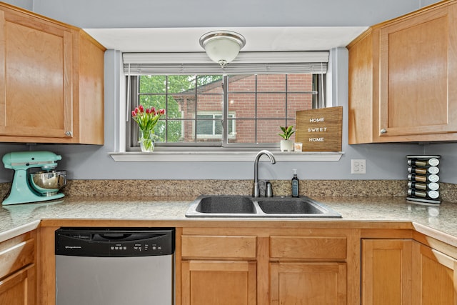 kitchen with stainless steel dishwasher, a sink, and light countertops