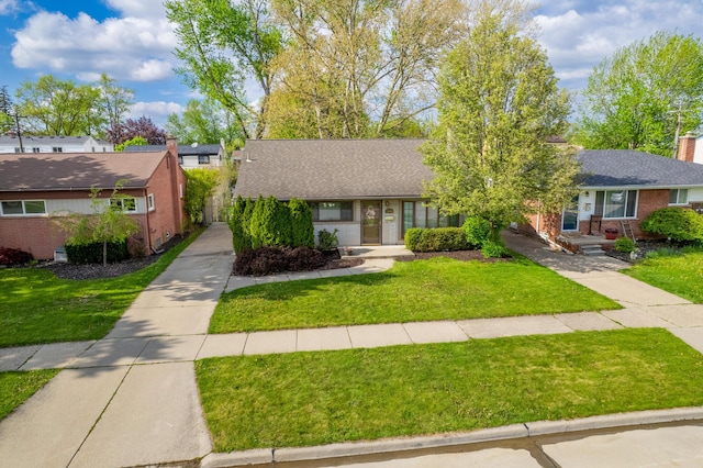 view of front of house featuring brick siding, a front yard, a shingled roof, and a chimney