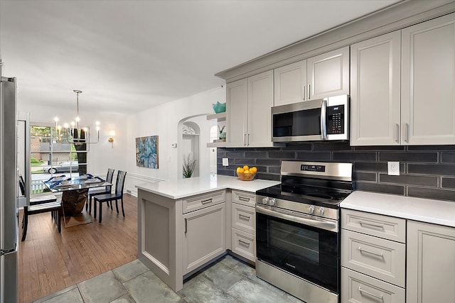 75 Grosse Pointe Blvd, Grosse Pointe Farms, MI 48236 - kitchen with stainless steel appliances, a peninsula, a chandelier, arched walkways, and decorative backsplash