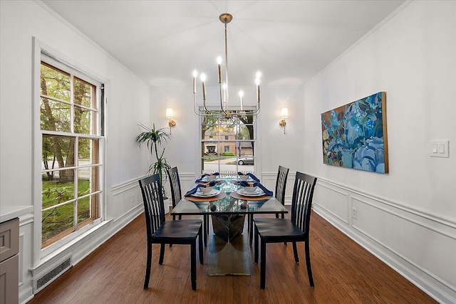 dining space with a chandelier, dark wood finished floors, plenty of natural light, a decorative wall, and ornamental molding