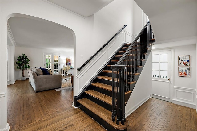 staircase featuring wood-type flooring, arched walkways, and crown molding