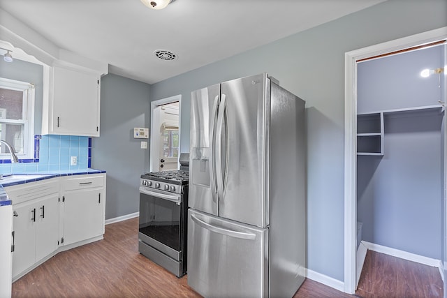 kitchen featuring stainless steel appliances, a sink, white cabinetry, and wood finished floors