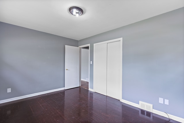 unfurnished bedroom featuring baseboards, wood finished floors, and a closet