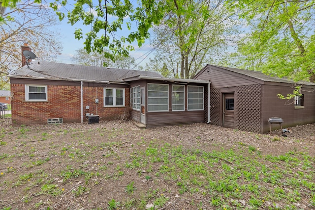 rear view of house featuring a sunroom and brick siding
