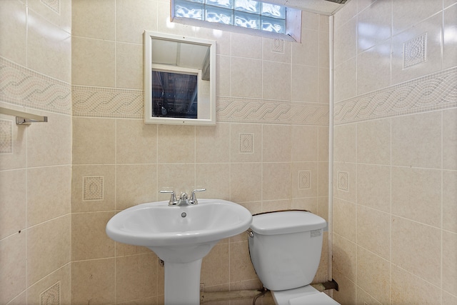 half bath featuring toilet and tile walls