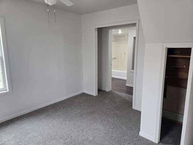 unfurnished bedroom with dark colored carpet and baseboards