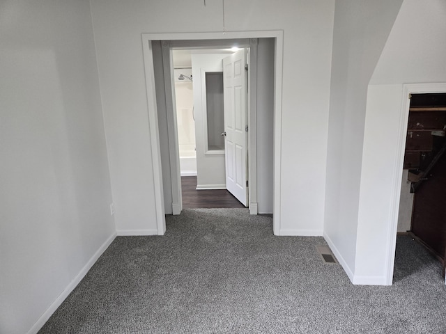 hallway with dark carpet and baseboards