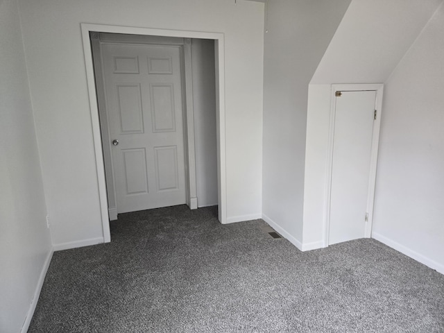 unfurnished bedroom with dark carpet and baseboards