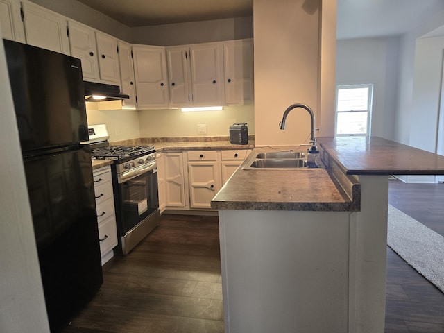 kitchen with stainless steel range with gas cooktop, freestanding refrigerator, a sink, a peninsula, and under cabinet range hood