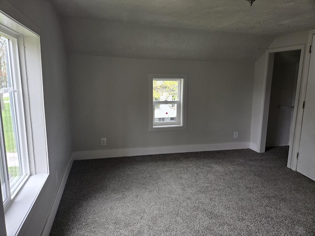 empty room with vaulted ceiling, carpet floors, and baseboards