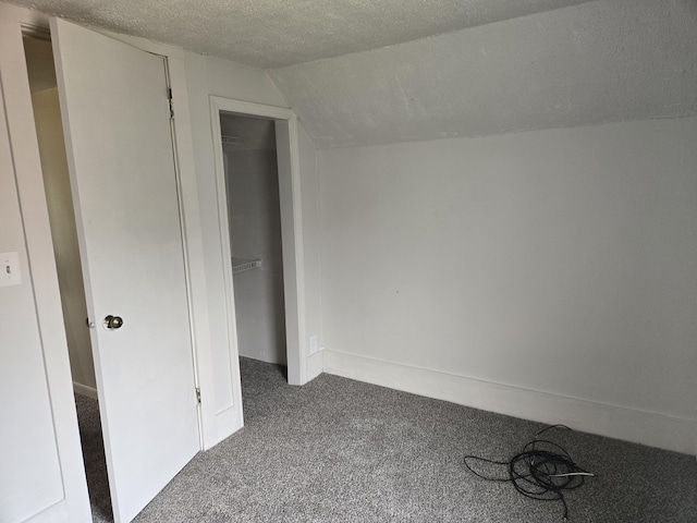 unfurnished bedroom with carpet floors, lofted ceiling, a textured ceiling, and a closet