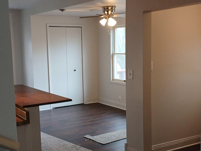 interior space featuring ceiling fan, baseboards, and dark wood-style floors