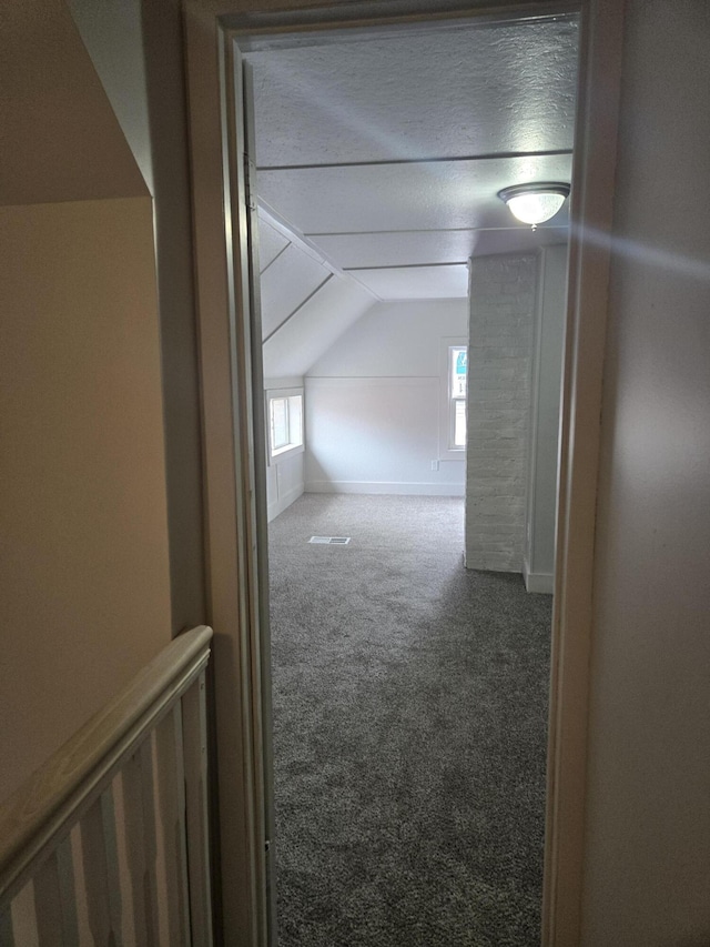 corridor featuring healthy amount of natural light, carpet floors, and vaulted ceiling