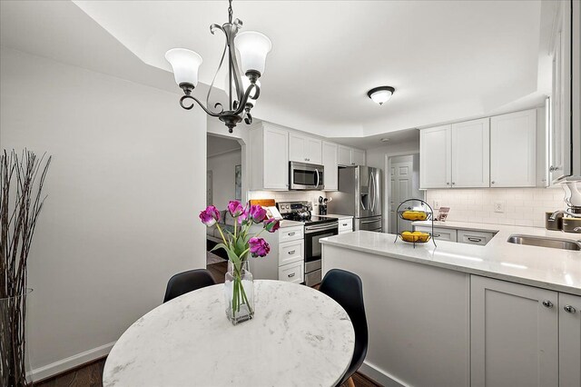 kitchen featuring stainless steel appliances, a sink, backsplash, and white cabinets