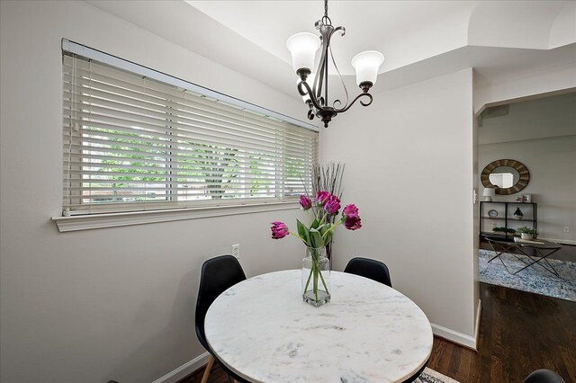 dining room featuring a chandelier, dark wood-type flooring, and baseboards