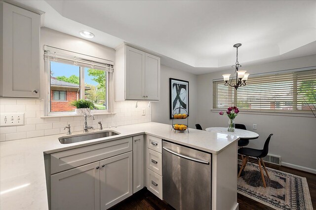 kitchen featuring a sink, dishwasher, a chandelier, decorative backsplash, and a peninsula