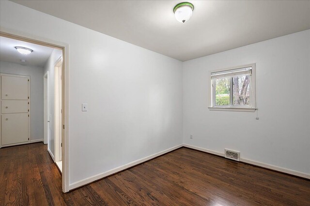 spare room featuring dark wood-style floors and baseboards