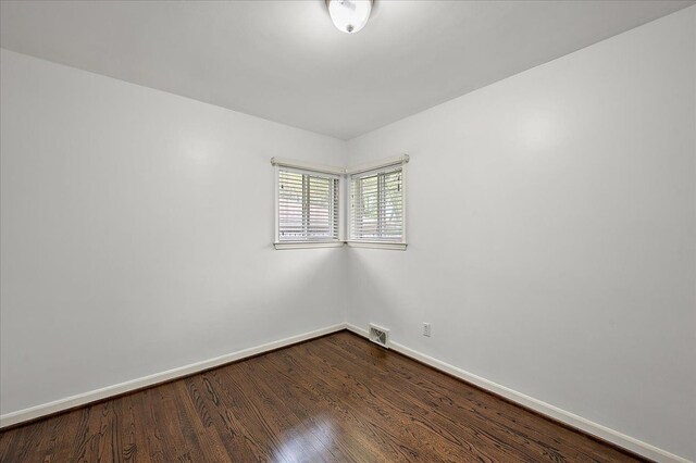 spare room with baseboards and dark wood-style flooring
