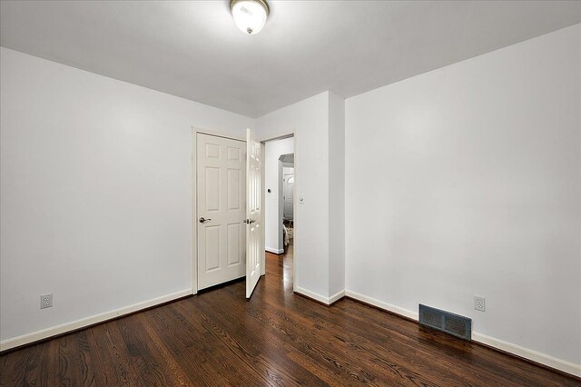 unfurnished room featuring baseboards and dark wood-style flooring