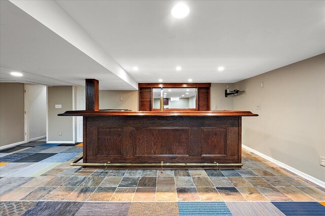 indoor wet bar with baseboards, recessed lighting, and dark stone finish flooring