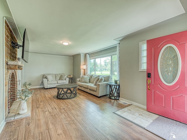 entryway featuring wood finished floors, baseboards, and a brick fireplace