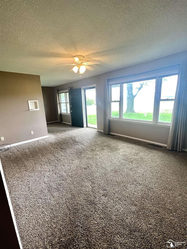 unfurnished room with a textured ceiling, ceiling fan, carpet, and baseboards