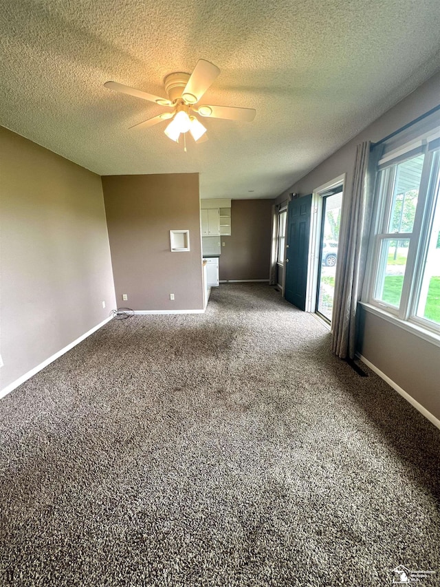 unfurnished living room with a ceiling fan, a textured ceiling, baseboards, and carpet flooring