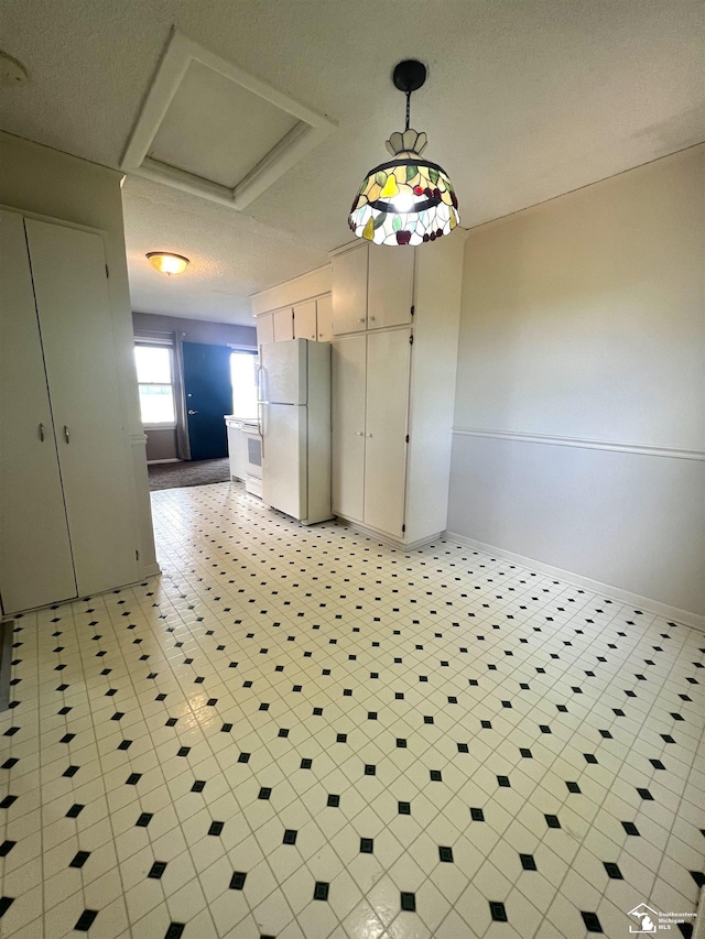 unfurnished dining area with attic access, baseboards, and a textured ceiling