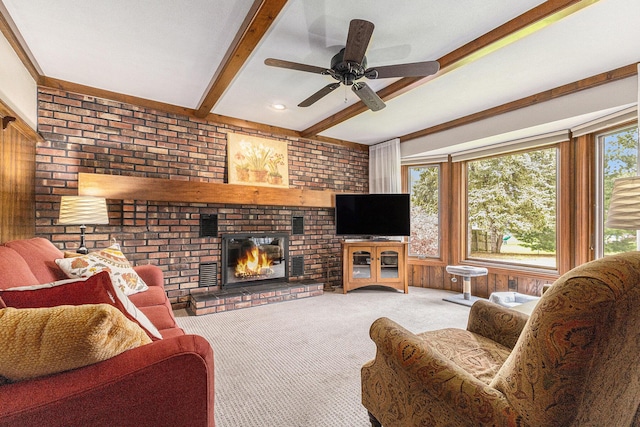 living room featuring beamed ceiling, carpet flooring, a fireplace, and a ceiling fan