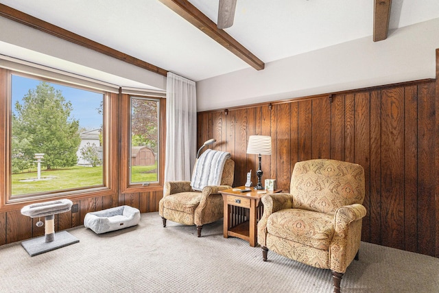 sitting room with beam ceiling, carpet, and wood walls