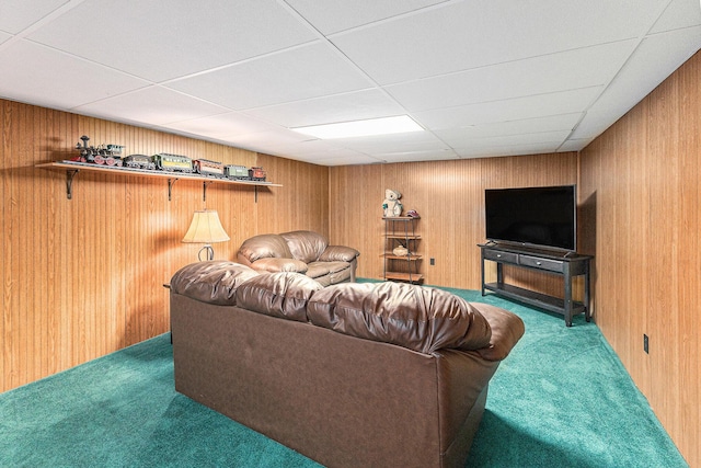 living room with carpet, wooden walls, and a drop ceiling
