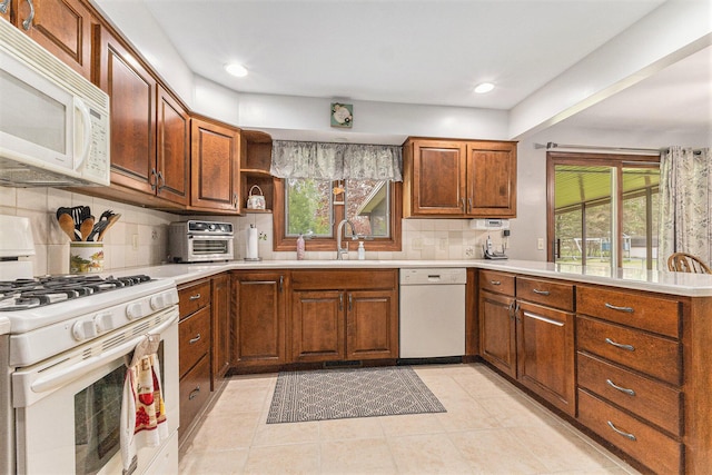 kitchen featuring white appliances, a sink, plenty of natural light, decorative backsplash, and recessed lighting