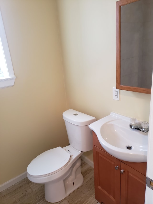 bathroom with wood finished floors, toilet, vanity, and baseboards