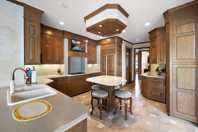 kitchen featuring a sink, a kitchen bar, light countertops, recessed lighting, and a center island