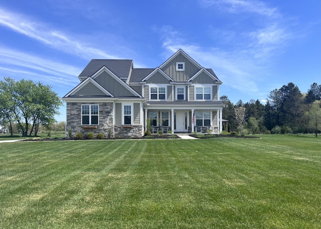 craftsman inspired home with board and batten siding, a front lawn, covered porch, and stone siding