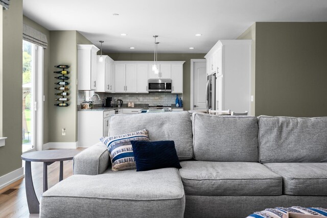 living room featuring light wood finished floors, baseboards, and recessed lighting