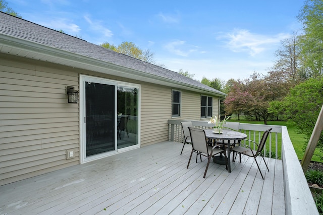 wooden terrace with outdoor dining space and a lawn