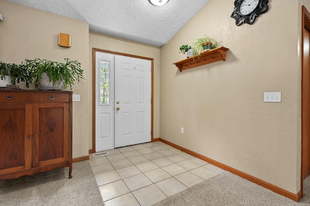 foyer with a textured ceiling, baseboards, and a textured wall