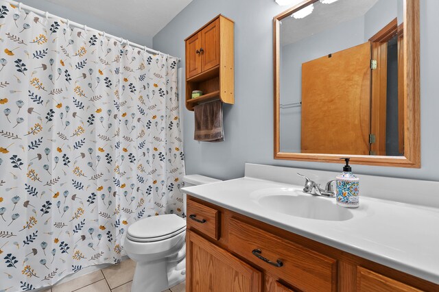 bathroom featuring toilet, tile patterned floors, vanity, and curtained shower