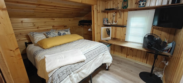 bedroom with wood walls, light wood-style floors, vaulted ceiling, and wood ceiling
