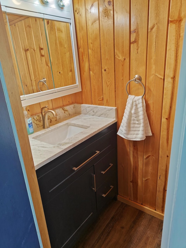 bathroom featuring wood finished floors, vanity, and wooden walls