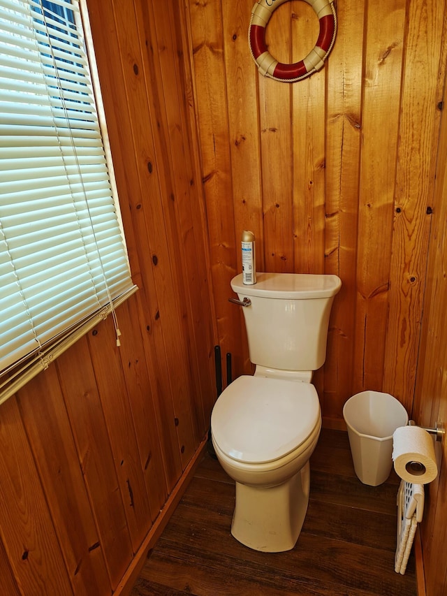 bathroom with wood finished floors, toilet, wooden walls, and baseboards