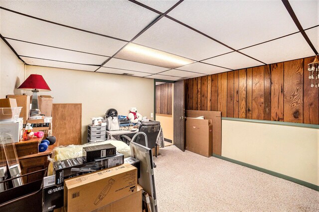 finished below grade area with carpet, wooden walls, and a paneled ceiling
