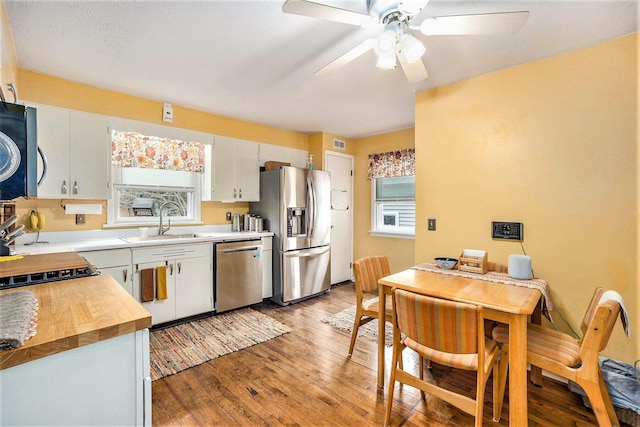 kitchen with stainless steel appliances, a sink, light wood finished floors, ceiling fan, and white cabinetry