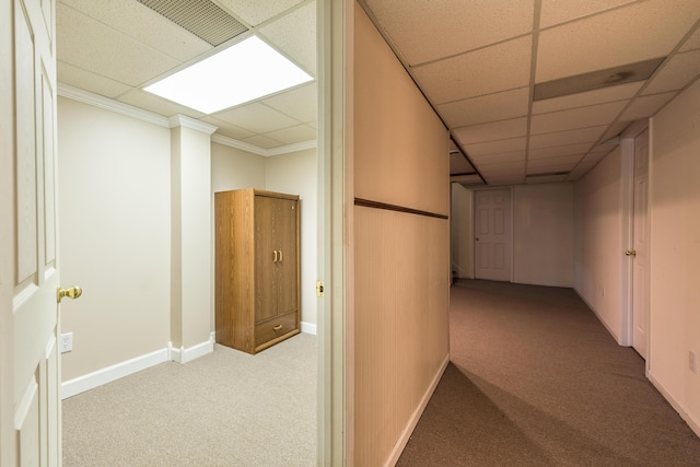 corridor with a paneled ceiling, carpet, baseboards, and crown molding
