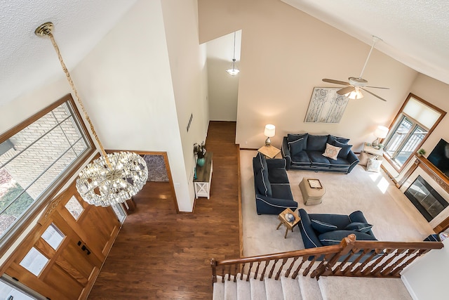 living room with high vaulted ceiling, wood finished floors, a ceiling fan, a textured ceiling, and a chandelier