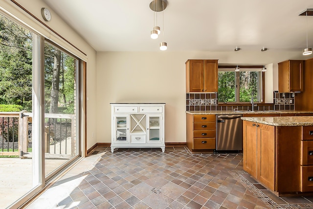 kitchen featuring dishwasher, a sink, brown cabinets, and plenty of natural light