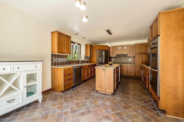 kitchen featuring appliances with stainless steel finishes, tasteful backsplash, brown cabinets, a sink, and a kitchen island