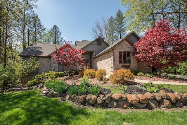 view of front of house featuring brick siding, a front lawn, and a shingled roof