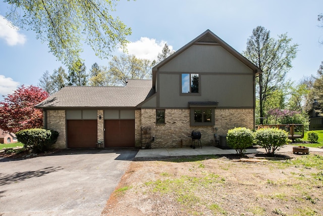 view of front facade with brick siding, asphalt driveway, an attached garage, and cooling unit